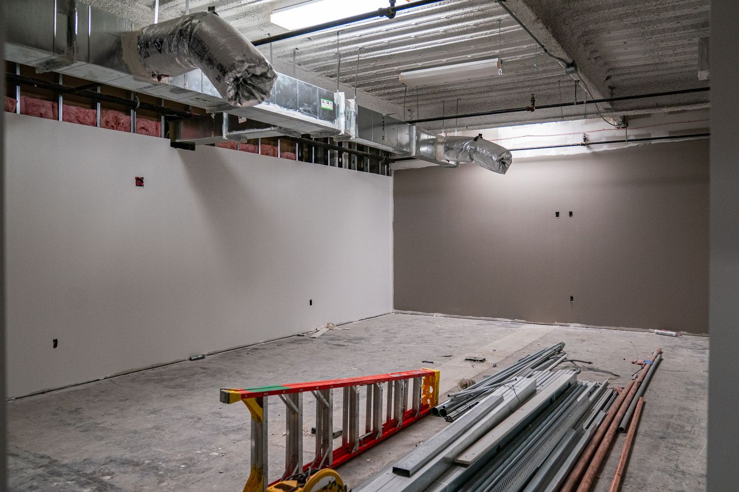 Unfinished commercial space with concrete floors and exposed mechanical systems.