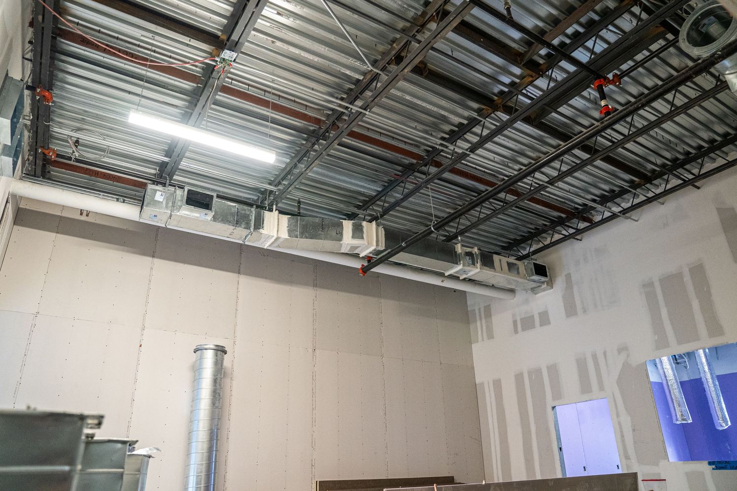 Commercial building interior showing metal stud framing and suspended ceiling grid installation.
