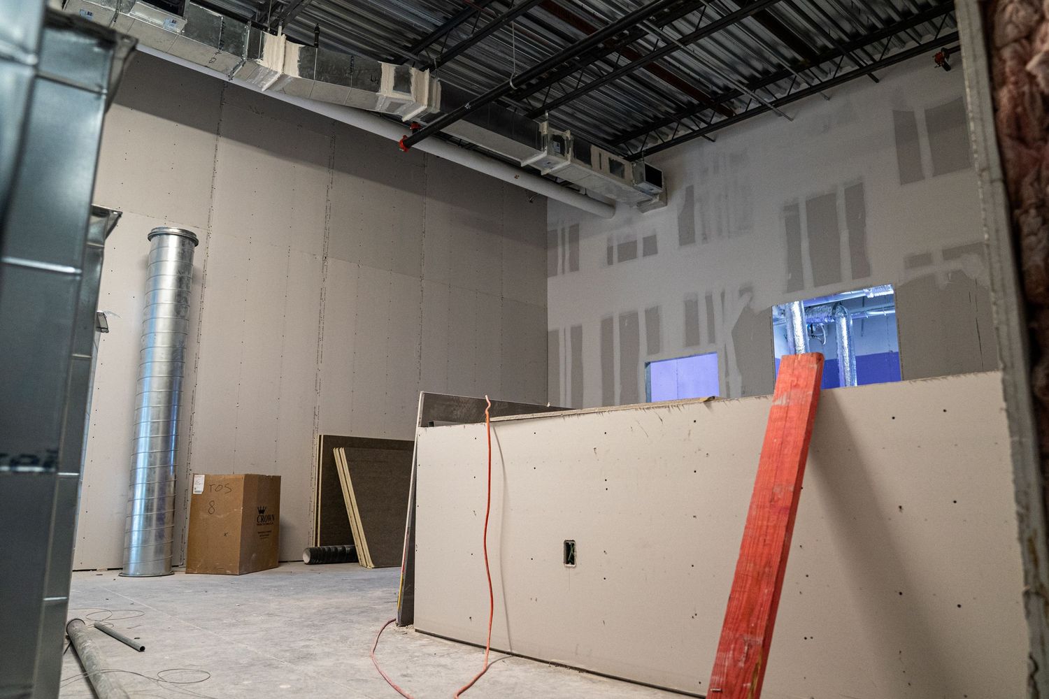 Unfinished commercial space with drywall panels and exposed mechanical systems.