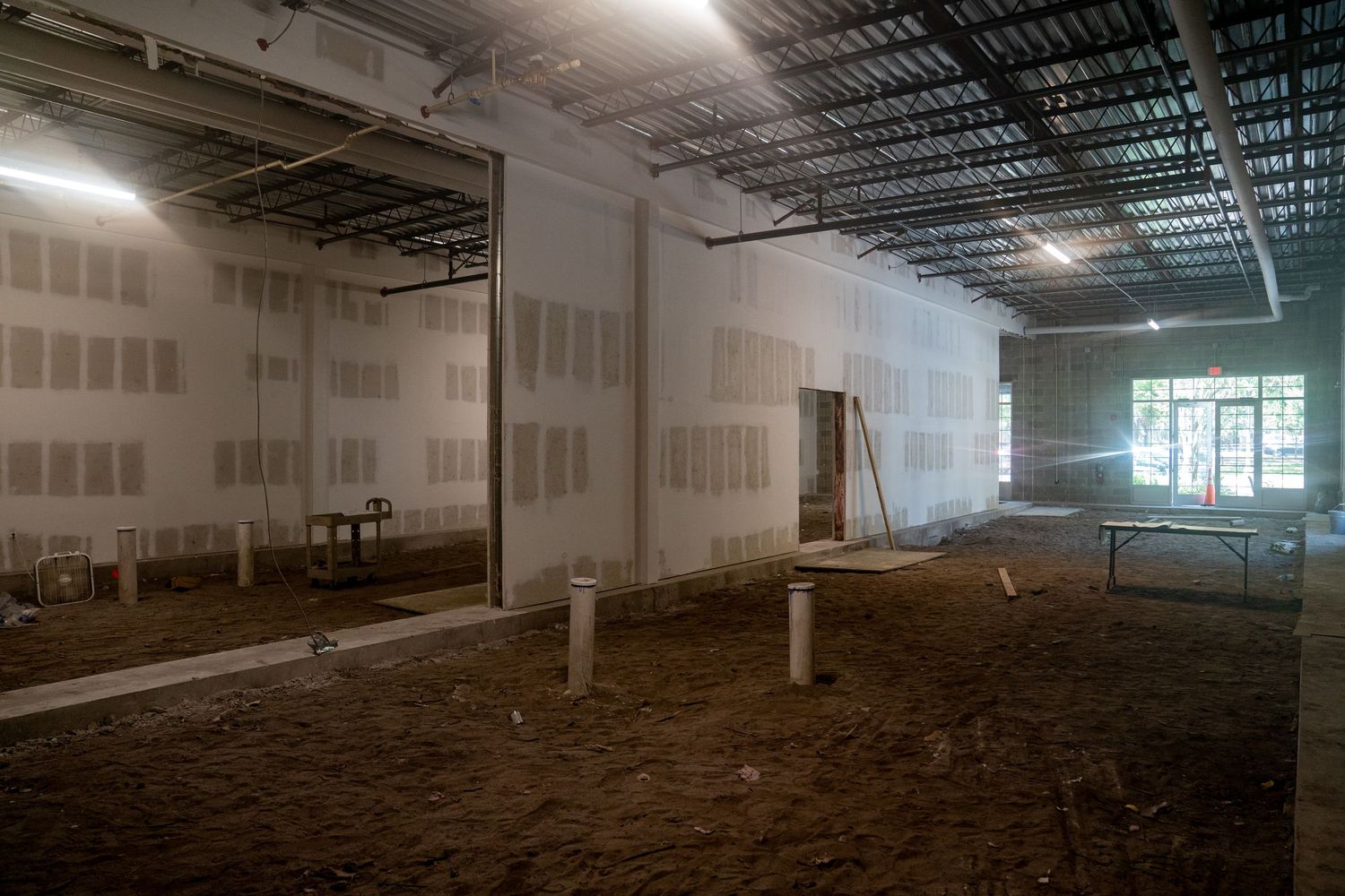 Large dark industrial space with exposed ceiling and fluorescent lighting fixtures.