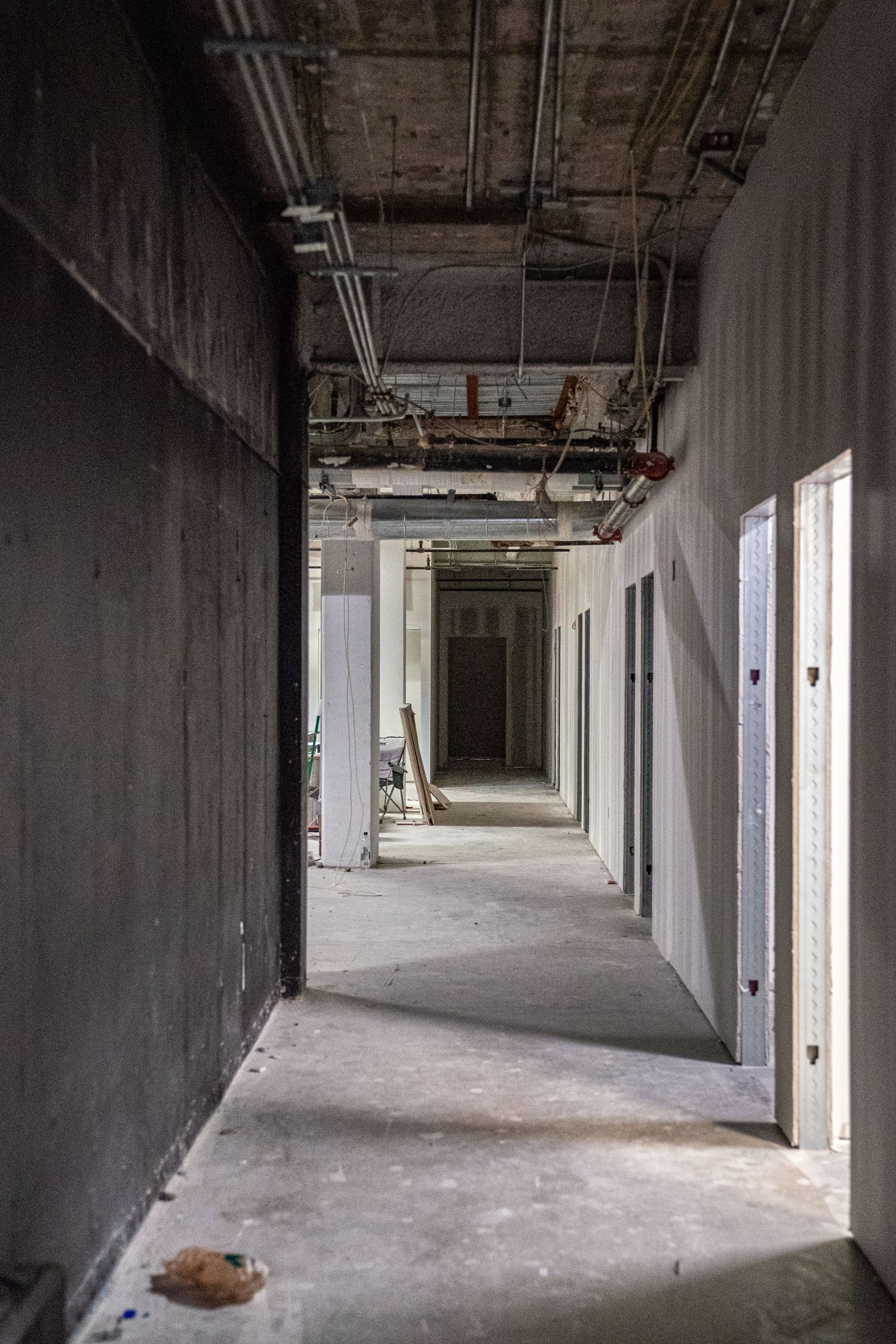 Unfinished commercial corridor with exposed concrete walls and utility systems visible.