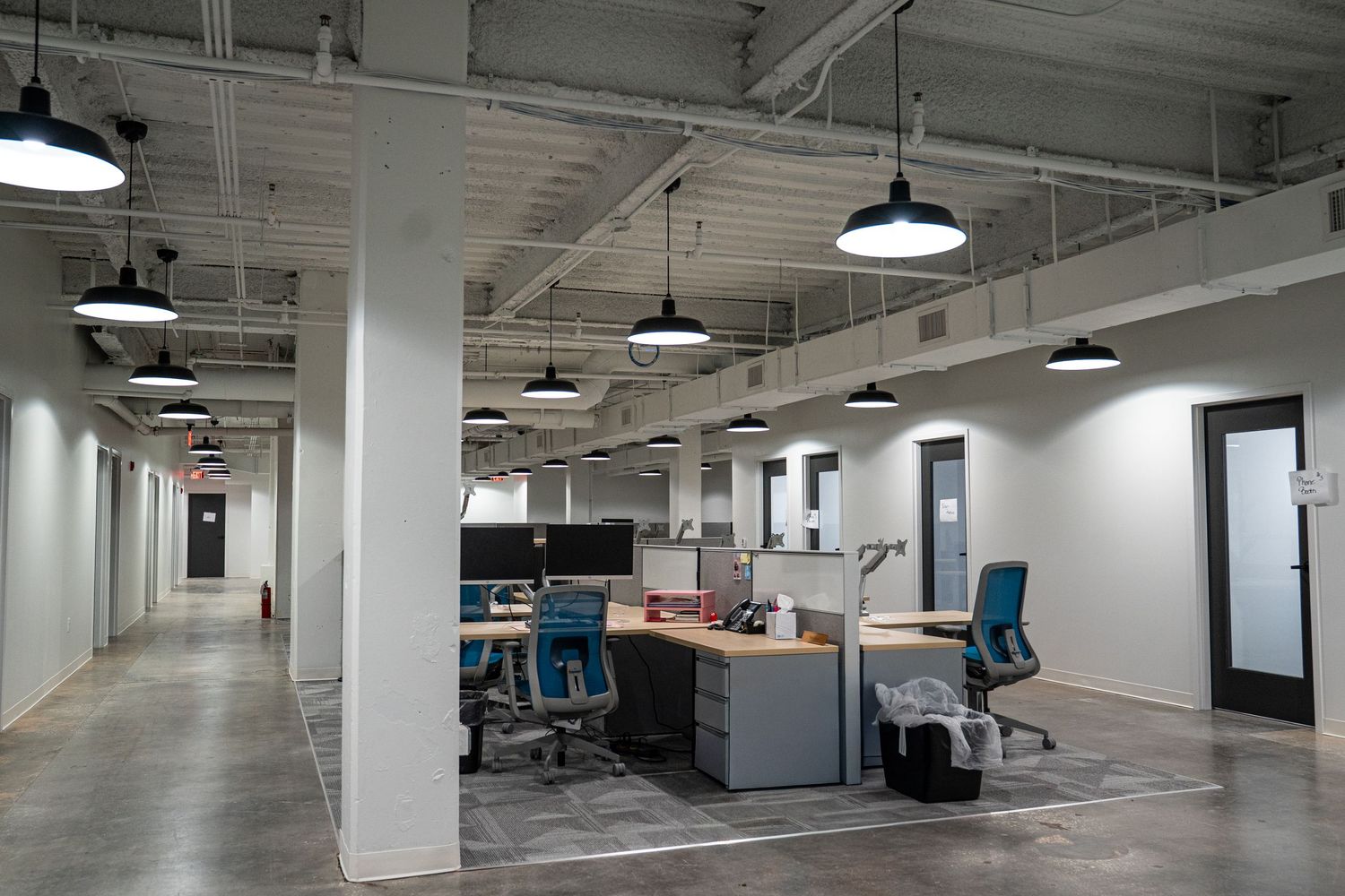 Open floor plan commercial space with industrial lighting and exposed mechanical systems.