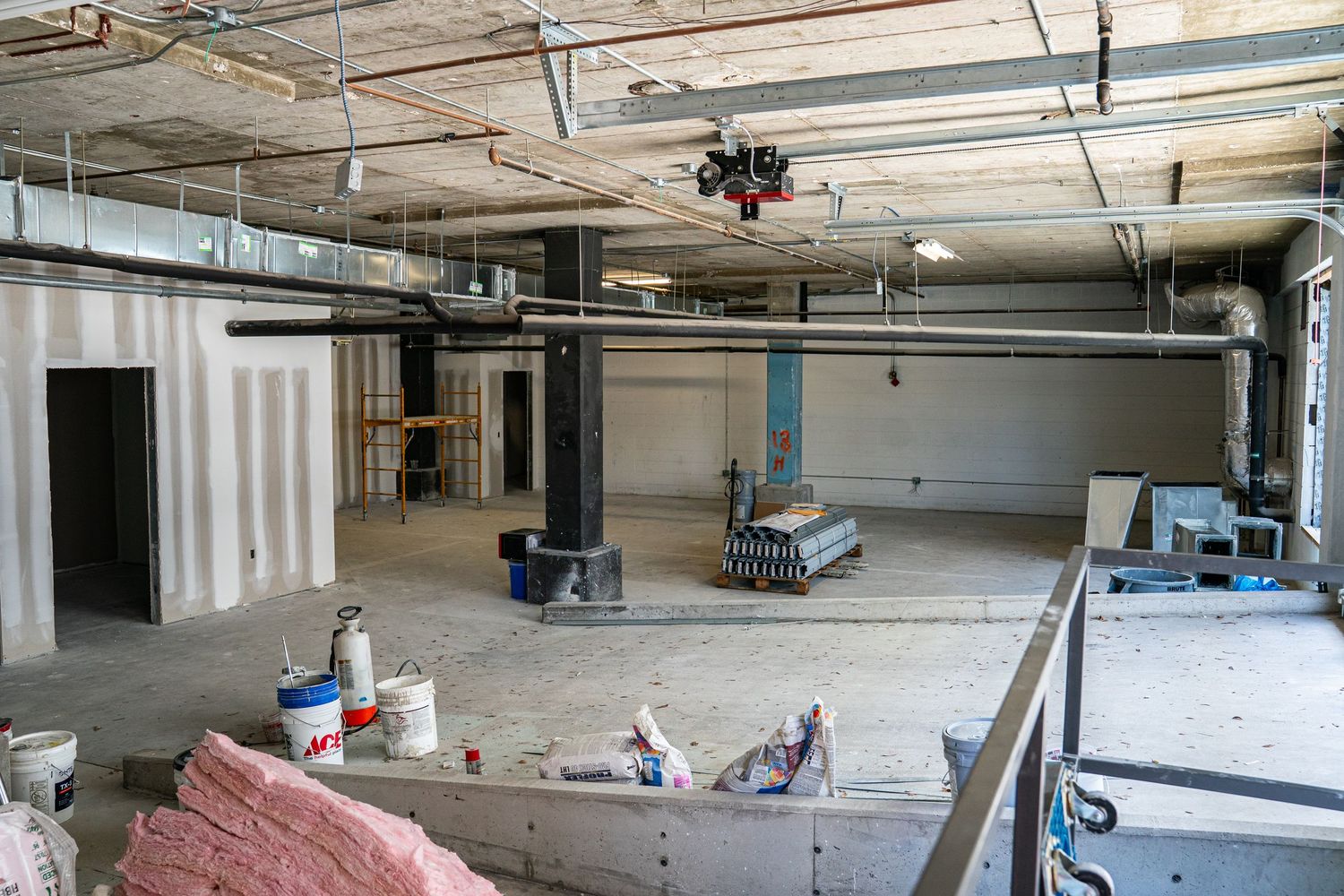 Large open warehouse space under construction with scattered building materials and equipment.