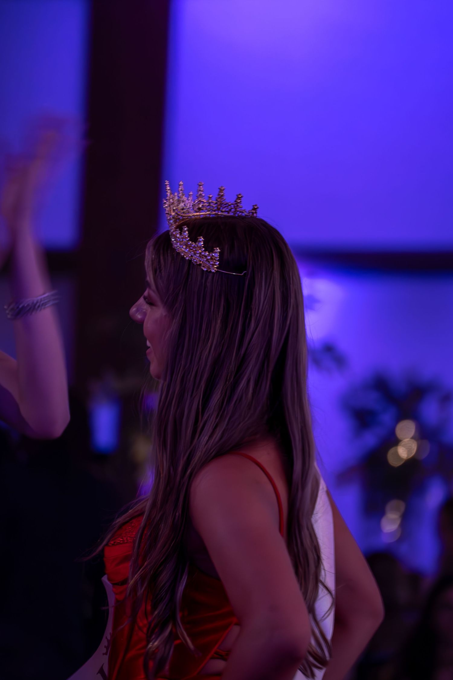 Formal event with purple lighting features attendees wearing decorative headpieces.