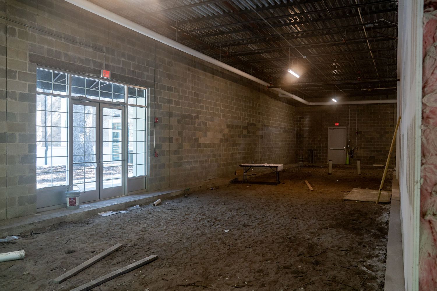 Empty retail space renovation showing concrete block walls and large window installation.