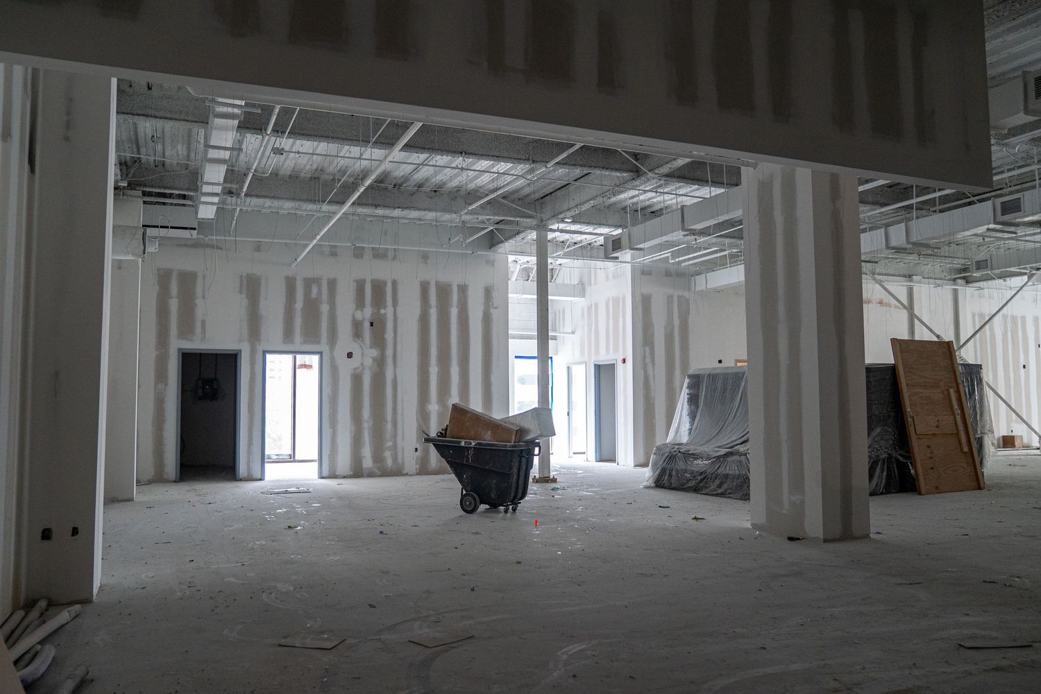 Large empty commercial space under construction with exposed ceiling and white walls.