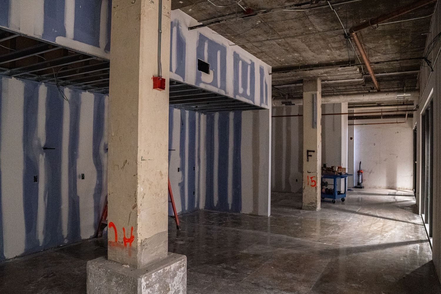 Panoramic view of commercial construction site with partial drywall installation.