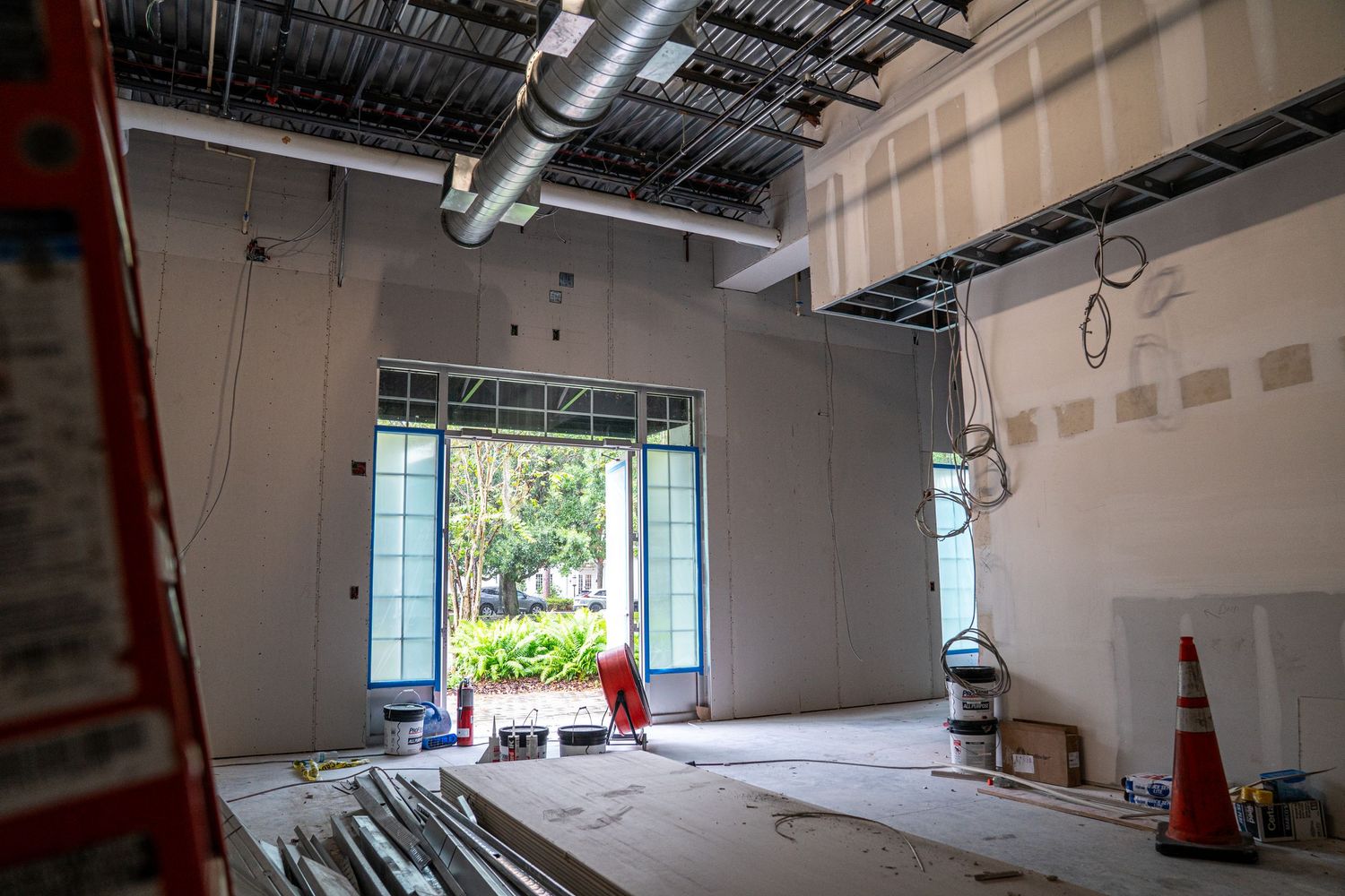 Panoramic view of commercial renovation with windows, ladders and unfinished ceiling infrastructure.