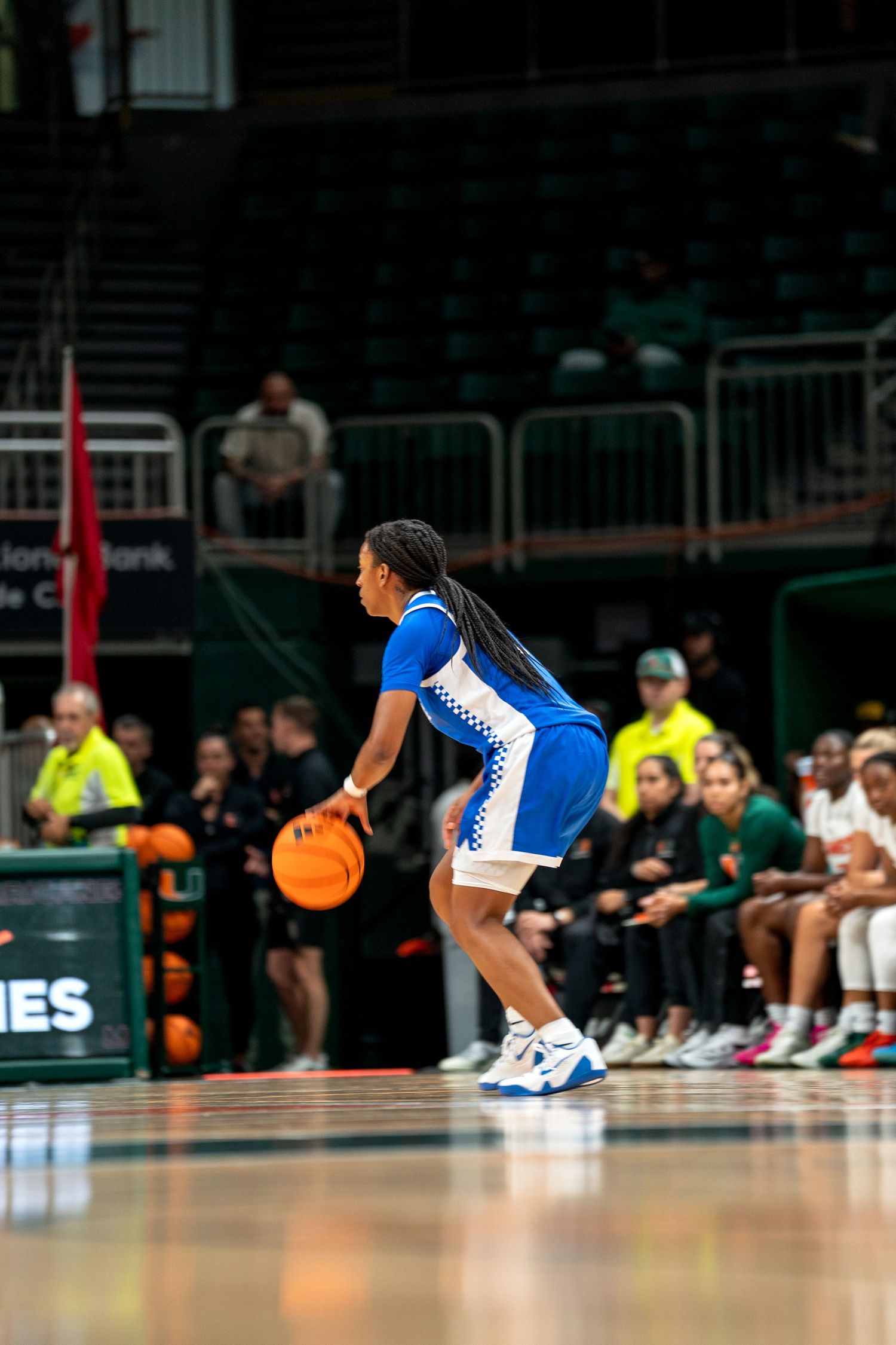 Basketball player in Kentucky uniform dribbles low during game action.