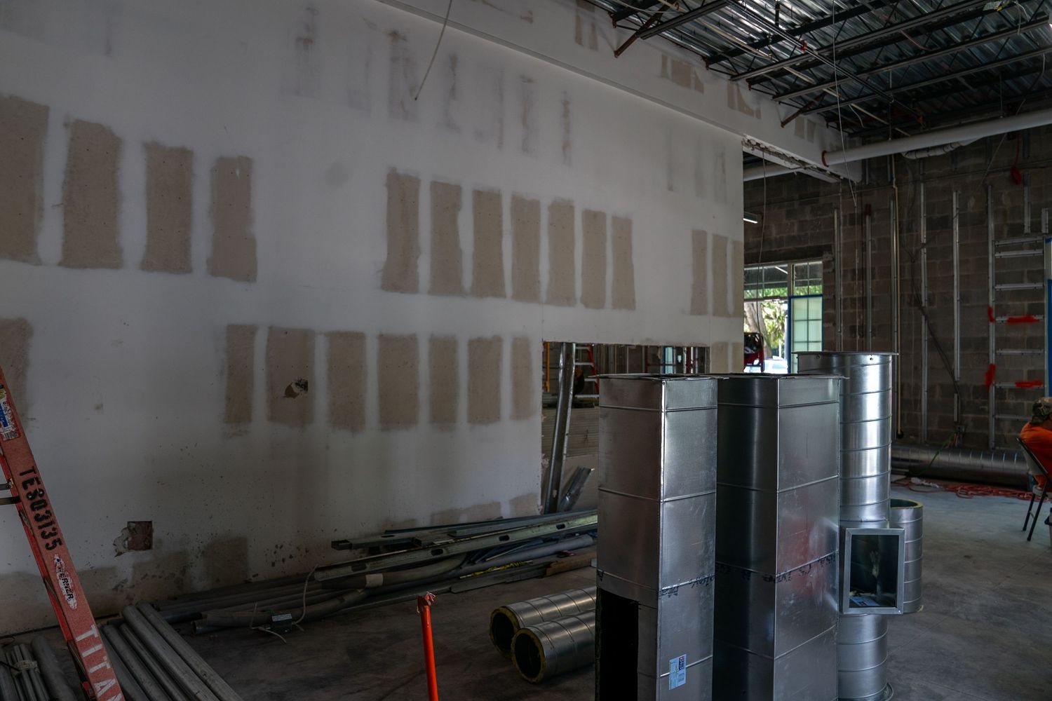 Interior construction progress showing drywall installation and metal framing work.