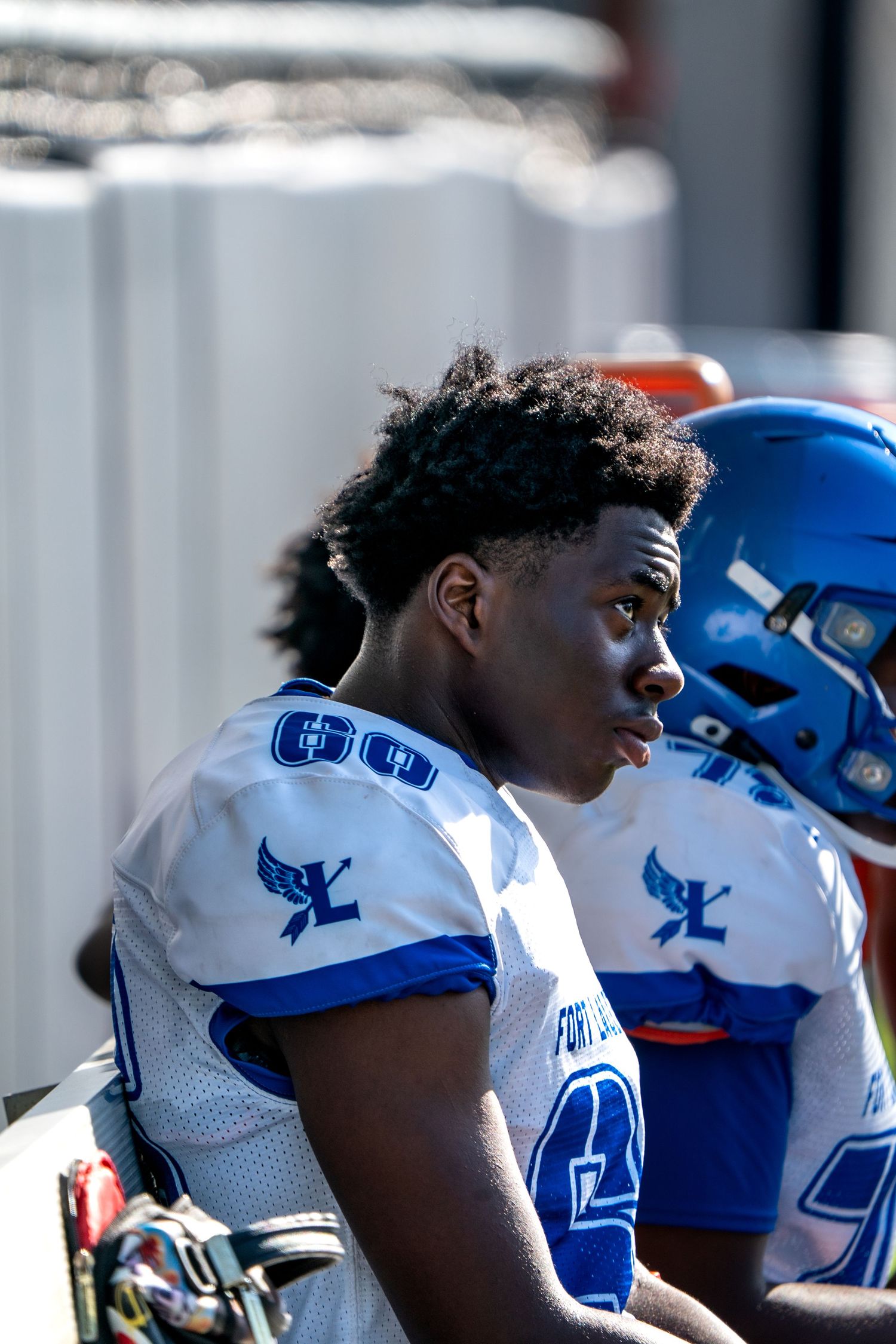 Football players in blue and white uniforms lined up on sideline during game.
