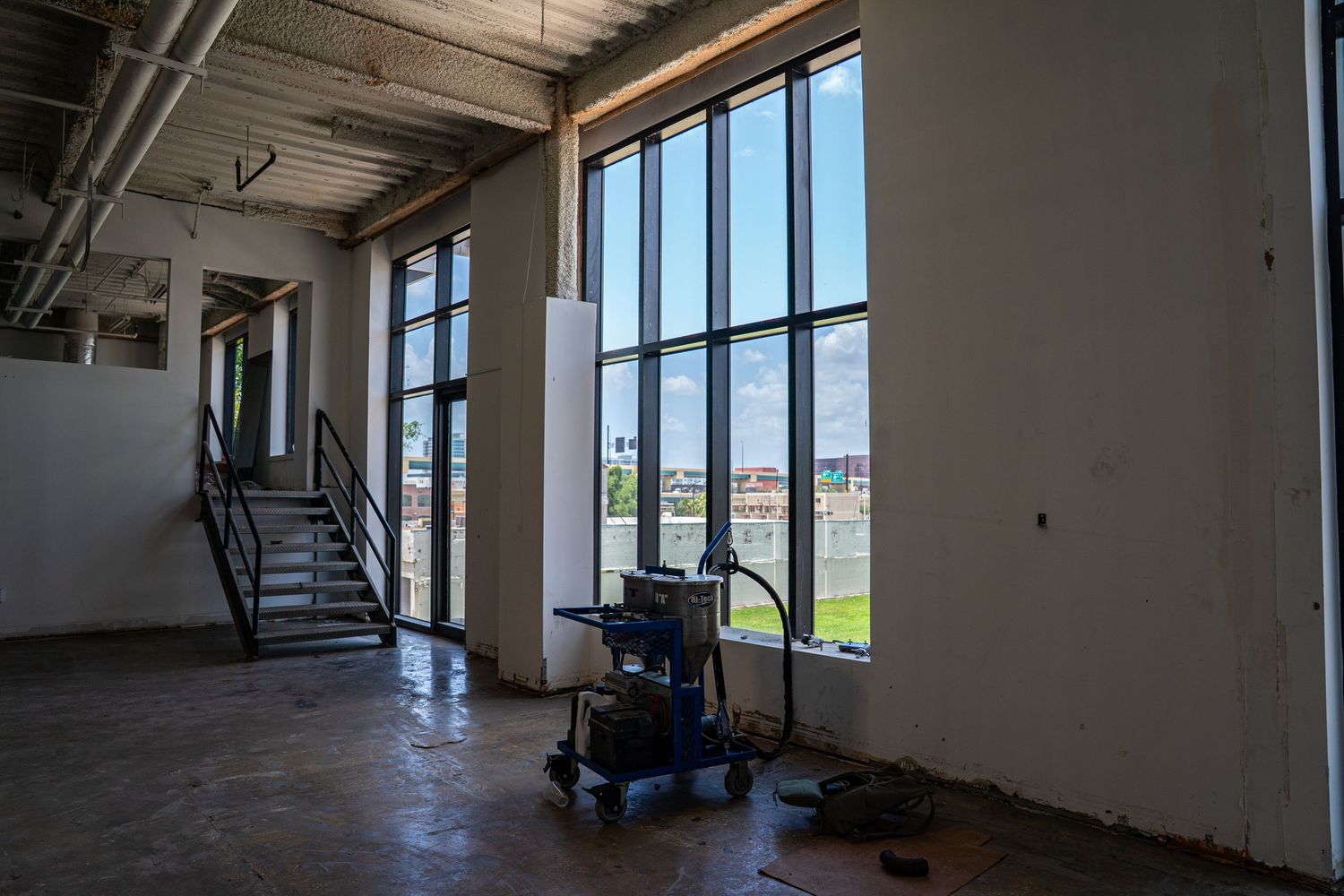 Open concept commercial interior with large windows and industrial ceiling features.
