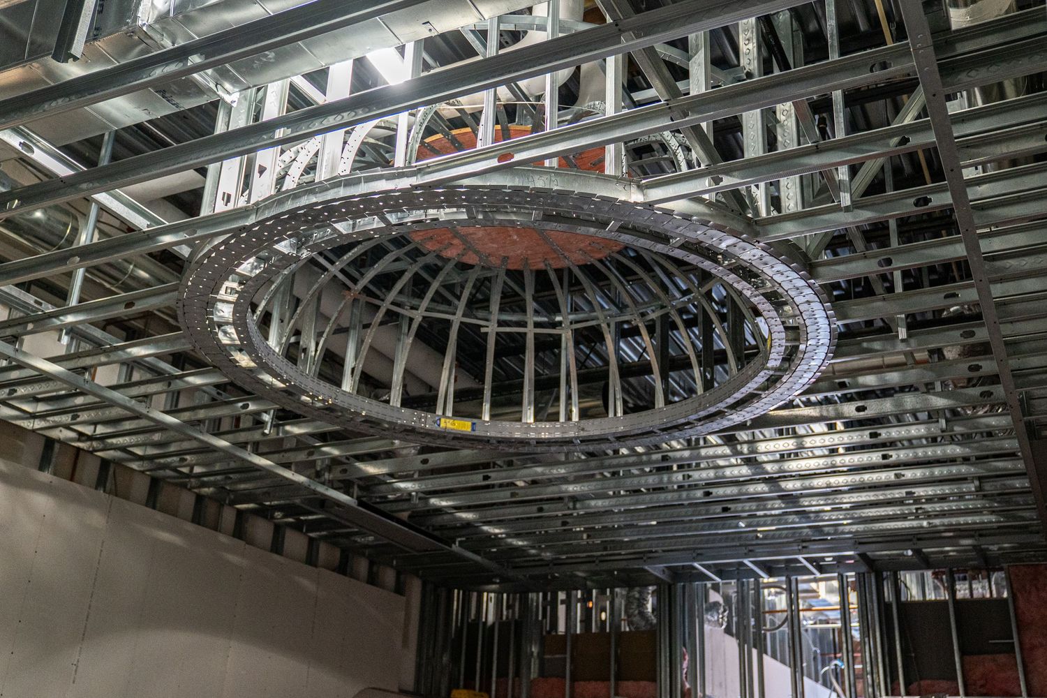 Detailed view of circular metal framework in ceiling during commercial construction project.