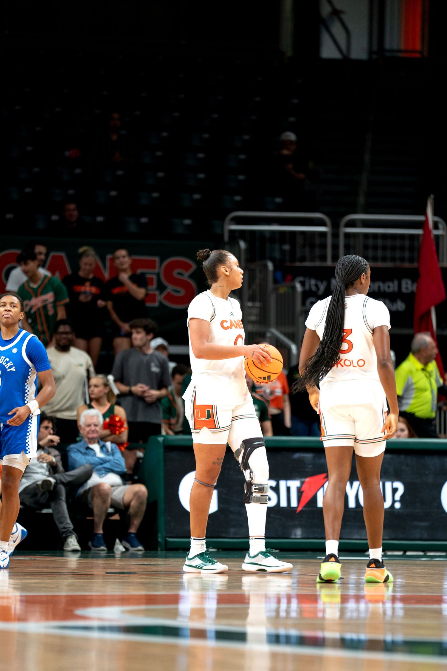 Basketball players line up on the court during a game at the Miami Hurricanes arena.