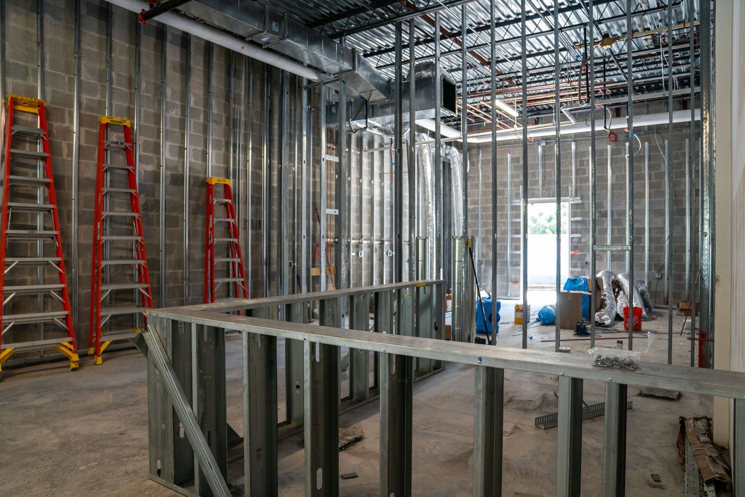 Construction progress showing metal framing and block walls in large commercial space.