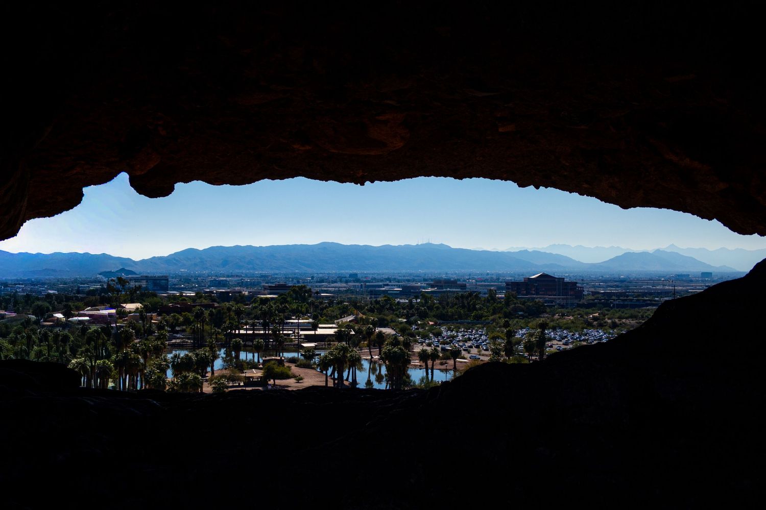 View of city and mountains through natural rock arch formation.