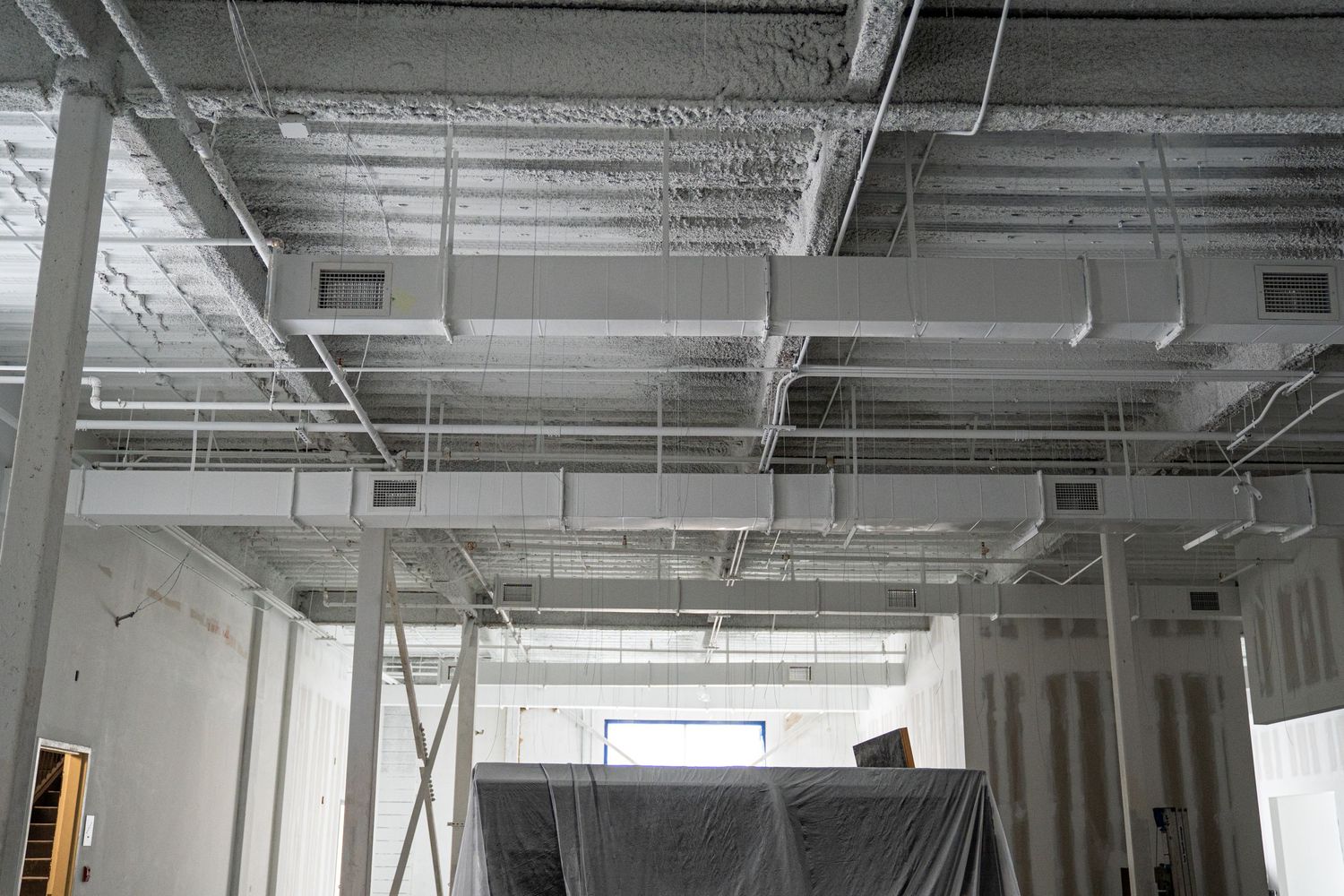 Industrial space with unfinished drywall and exposed ductwork in ceiling.