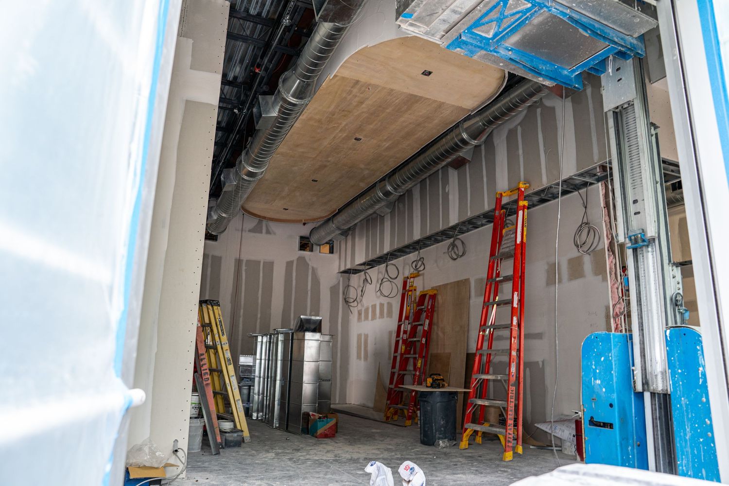 Unfinished commercial space with exposed metal framing and red ladders against walls.