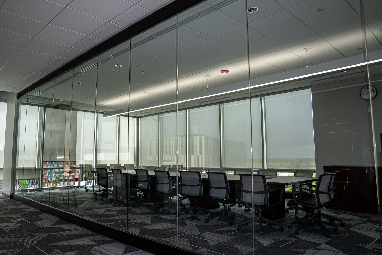 Contemporary office space with glass walls, ergonomic seating, and modern lighting fixtures.