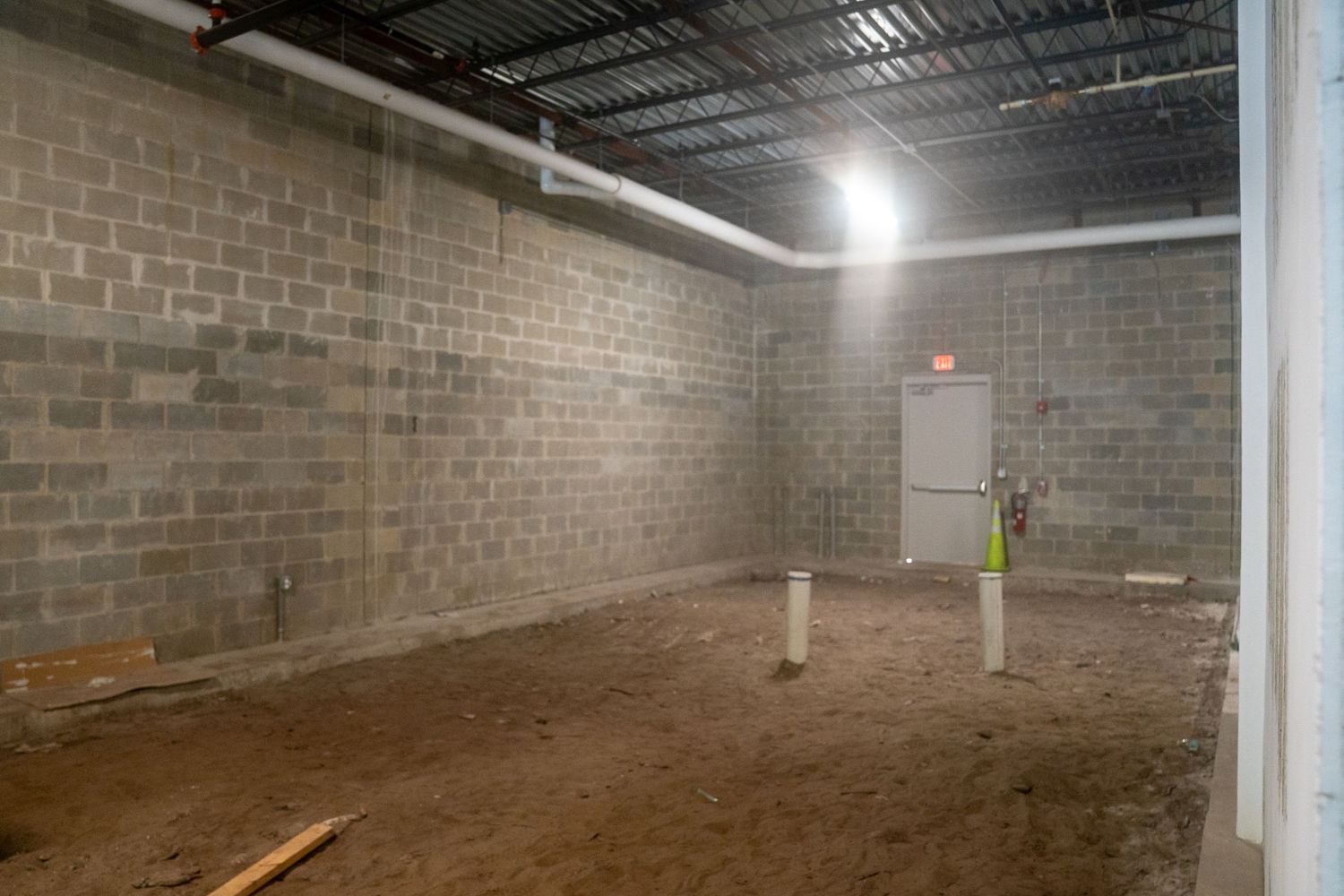 Unfinished industrial space with brick walls and concrete flooring during renovation.