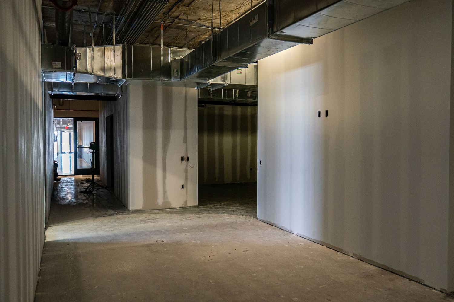 Long corridor view of commercial space under construction with natural lighting.