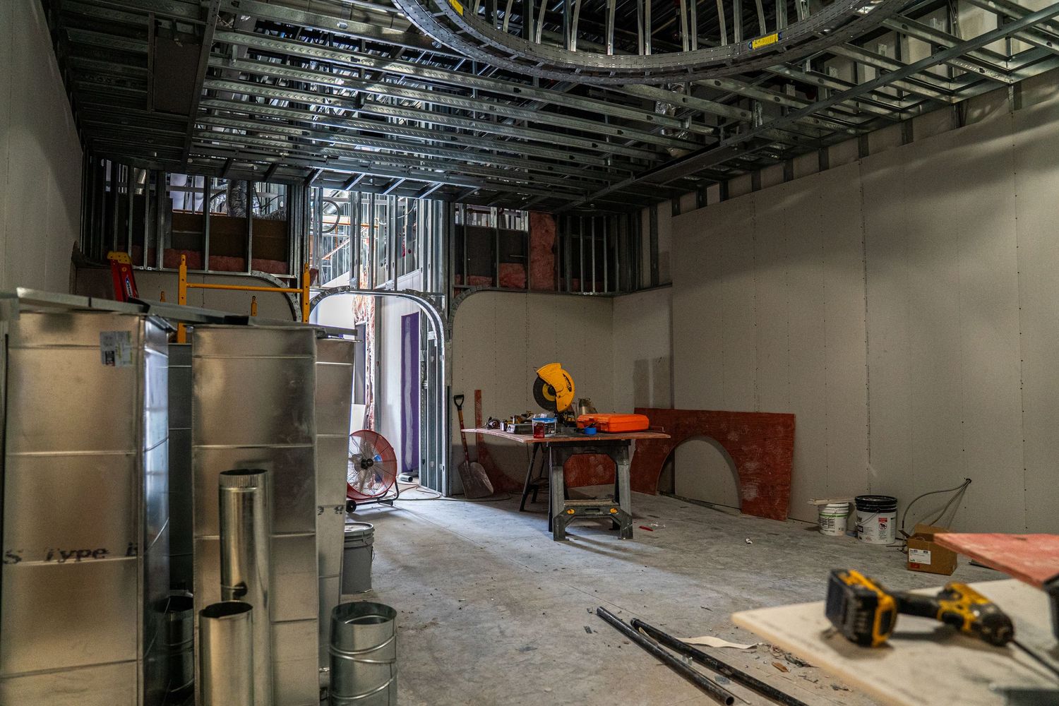 Dark industrial ceiling with exposed ductwork and mechanical systems during renovation.