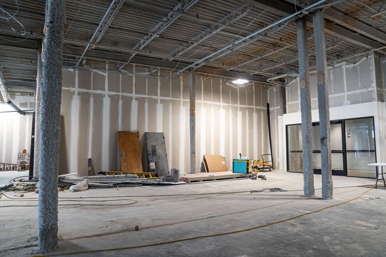 Empty commercial space under construction with exposed ceiling and concrete floors.