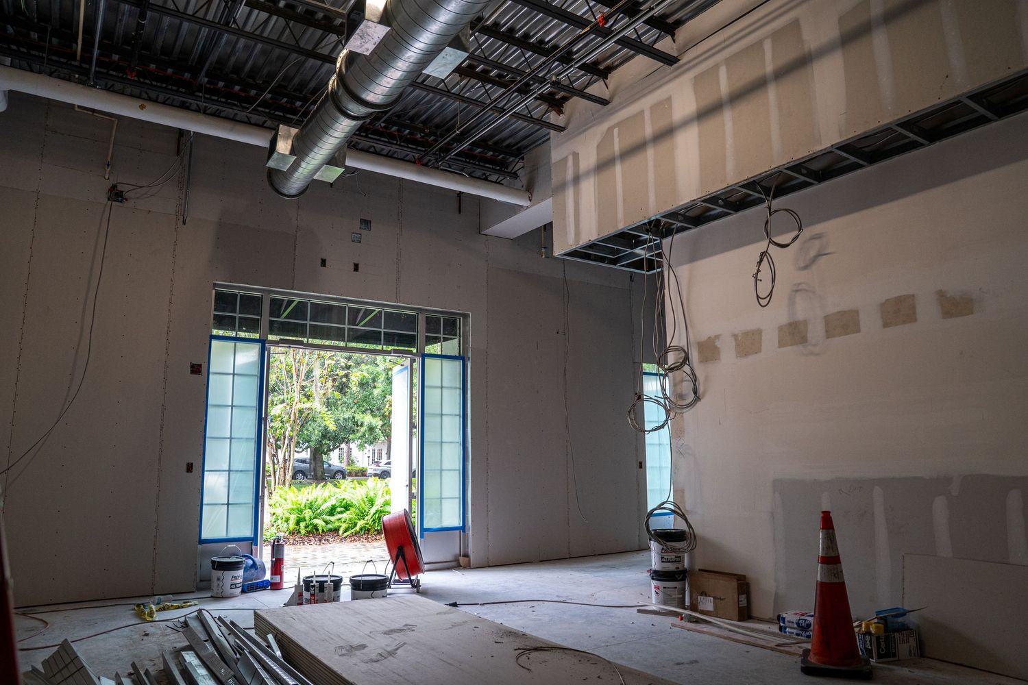 Commercial interior renovation with window views and red construction ladders visible.