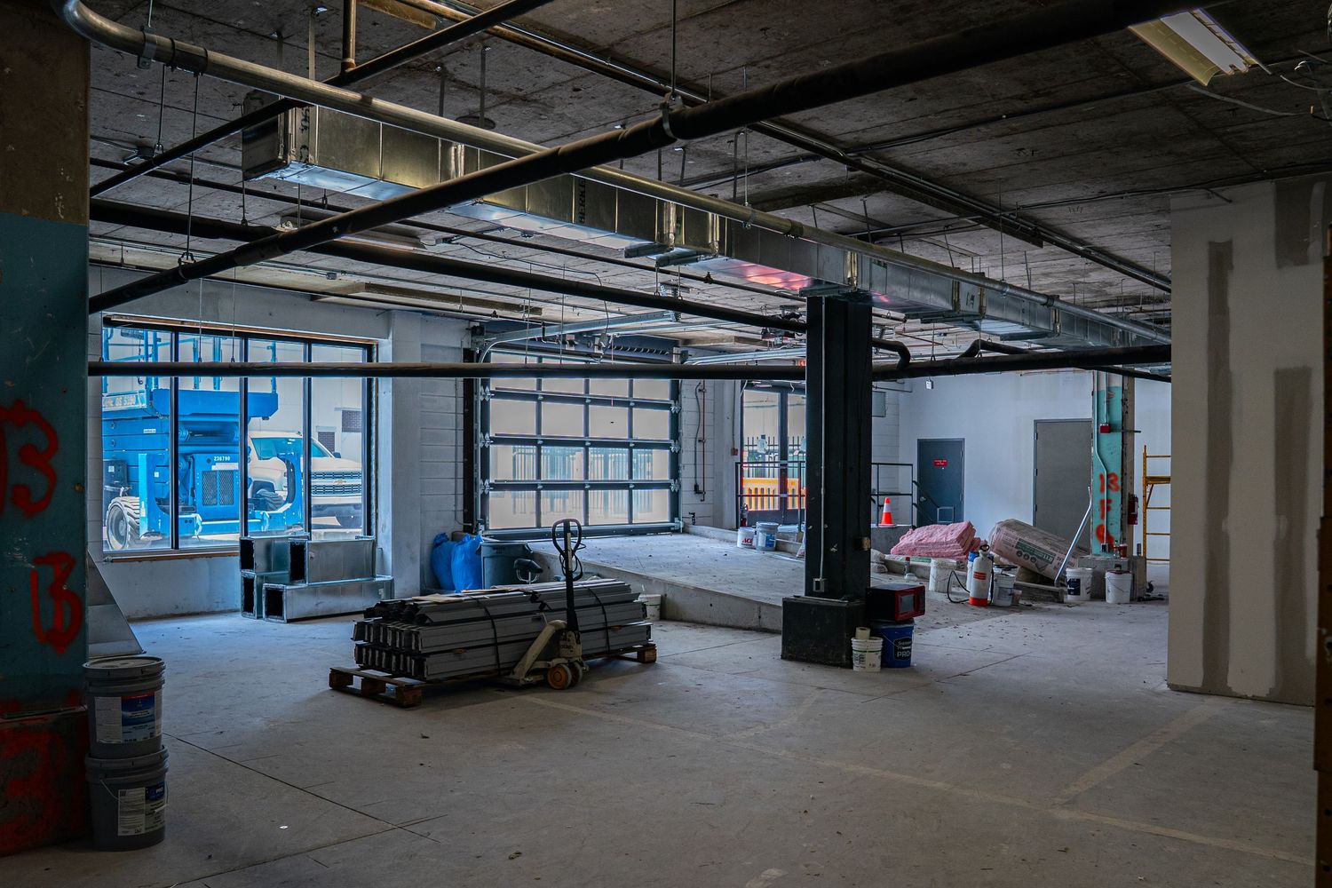 Large empty commercial space under construction with exposed ceiling and concrete floors.