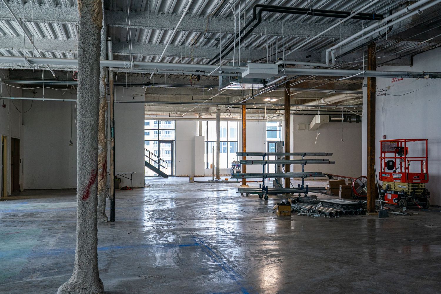 Raw commercial space under renovation showing concrete floors and exposed infrastructure.