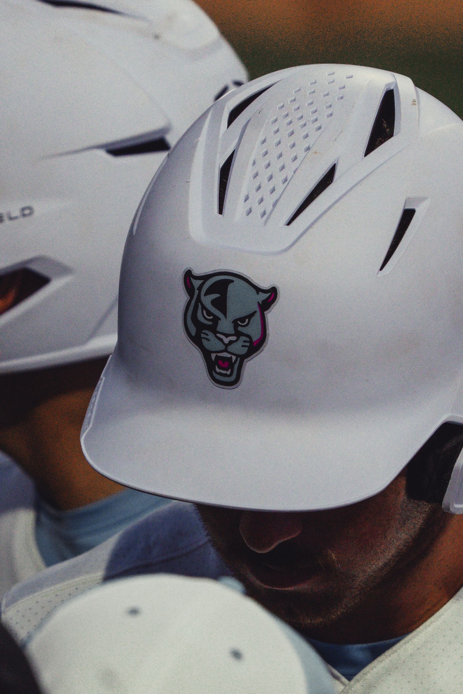 White baseball batting helmet featuring a fierce panther logo, worn by a player during a game.