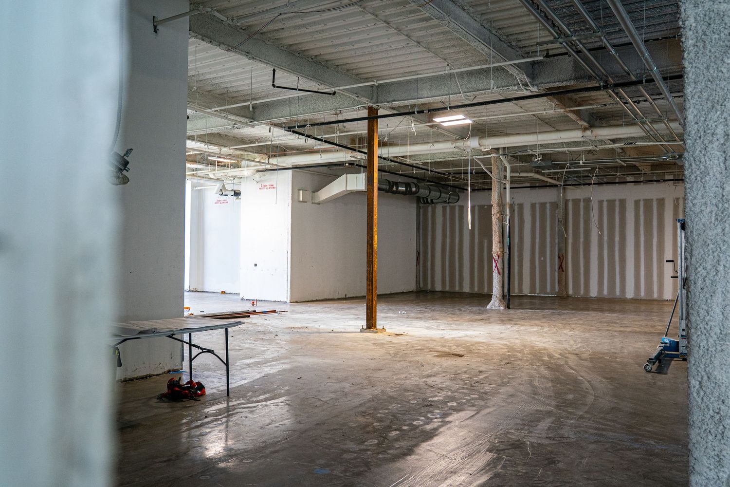 Open floor plan commercial space with industrial ceiling and concrete flooring.