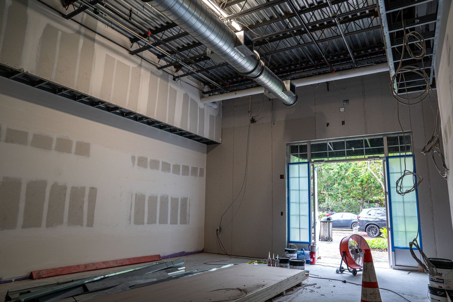 Spacious retail buildout showing drywall installation and industrial ceiling components.
