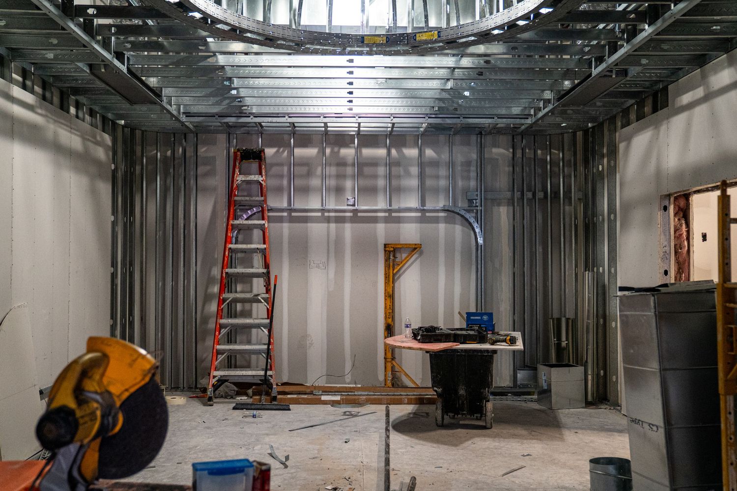 Construction site interior showing exposed metal framing, ductwork and utilities during commercial building renovation.