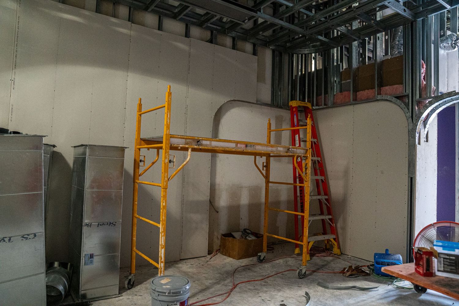 Industrial space with orange safety railings and construction equipment visible.