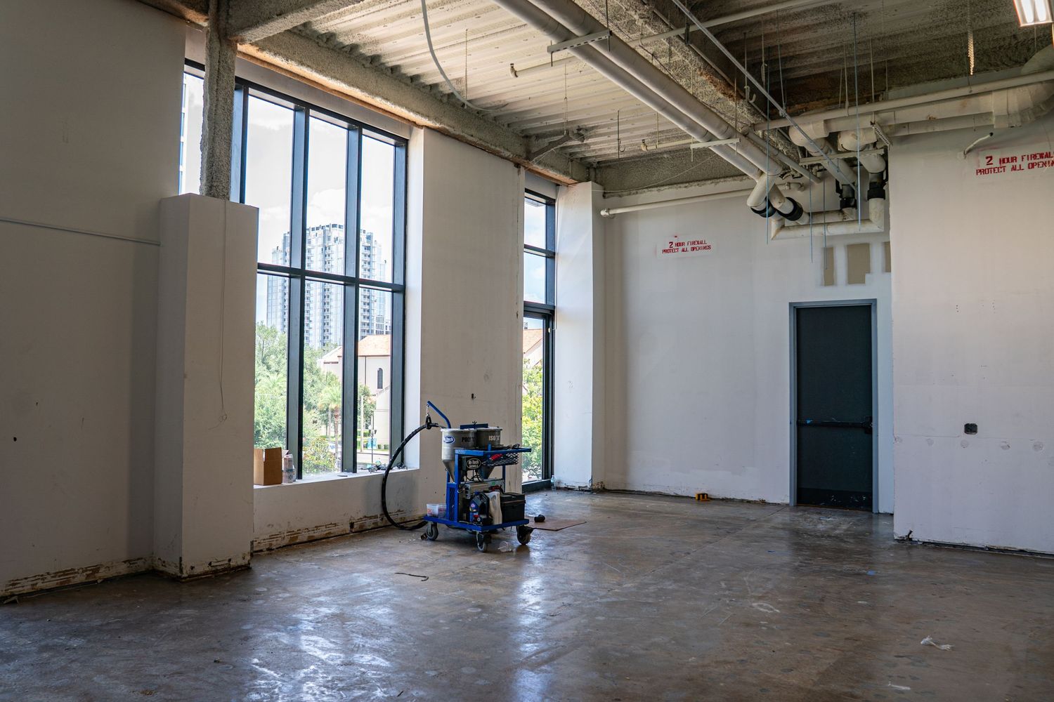 Large open office space with white walls and industrial lighting fixtures visible.