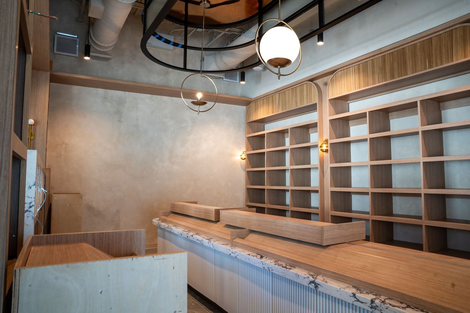 Modern office interior with wooden wall panels, built-in shelving, and pendant lighting creates a warm professional atmosphere.