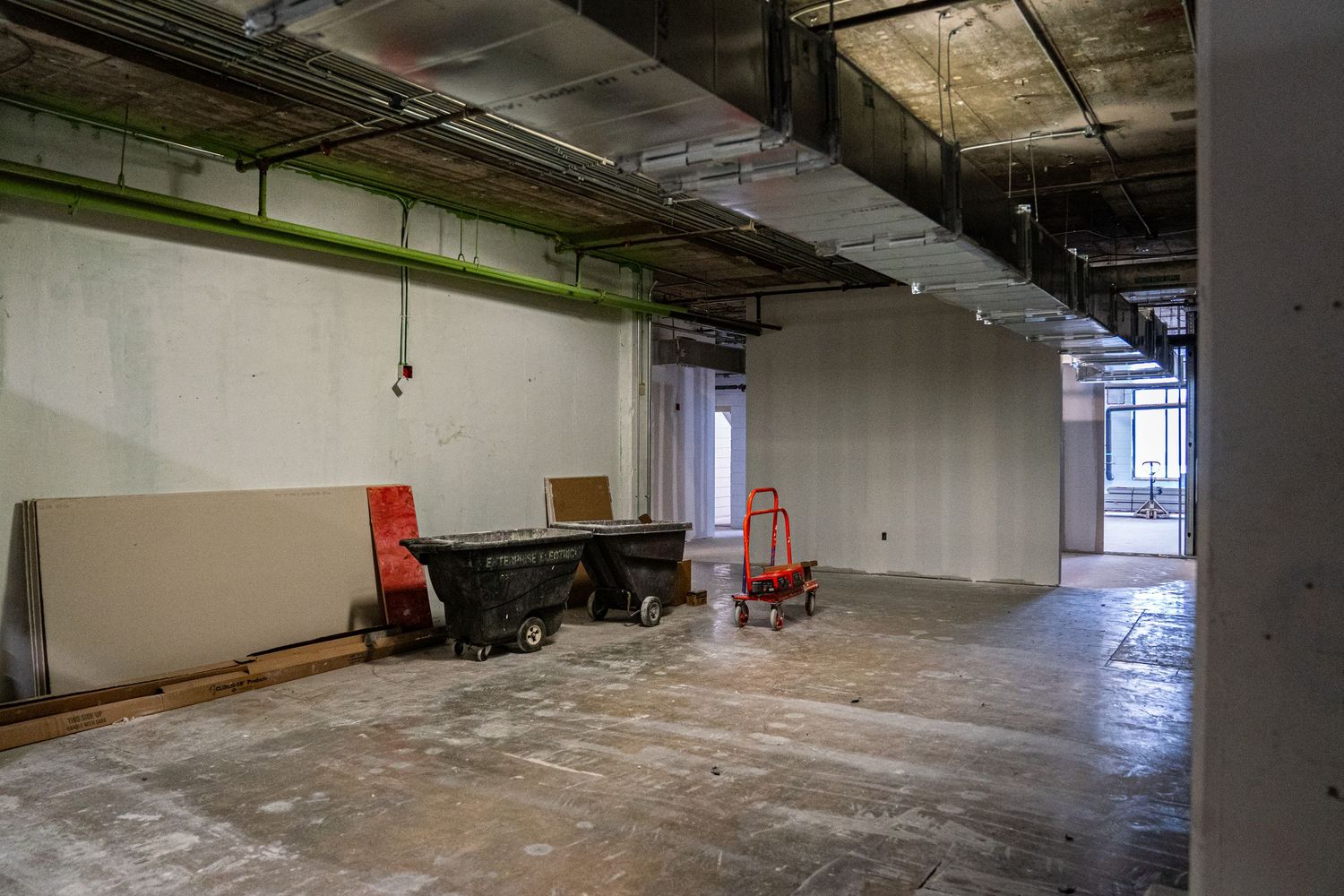 Large empty warehouse space with concrete floors and exposed ceiling infrastructure.
