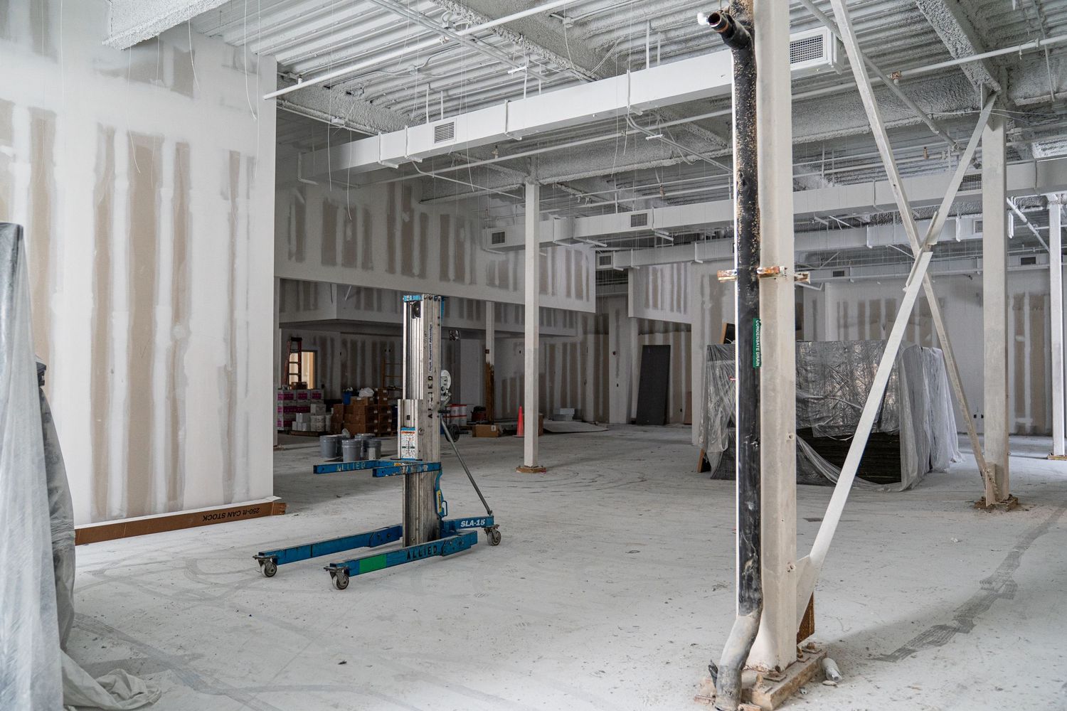 Commercial space renovation in progress with exposed structural elements and temporary lighting.