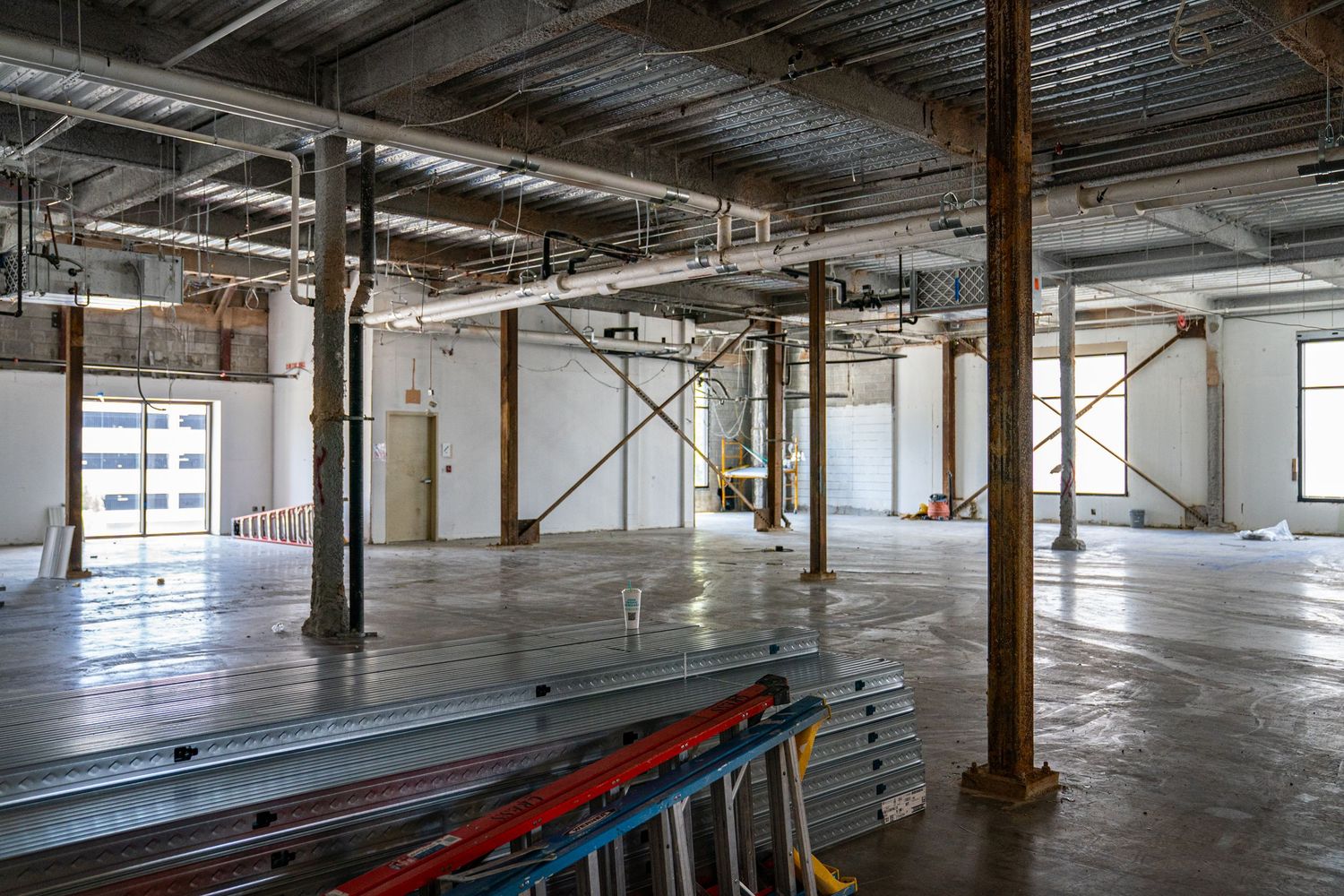 Panoramic view of an industrial warehouse interior with concrete pillars and exposed ductwork.