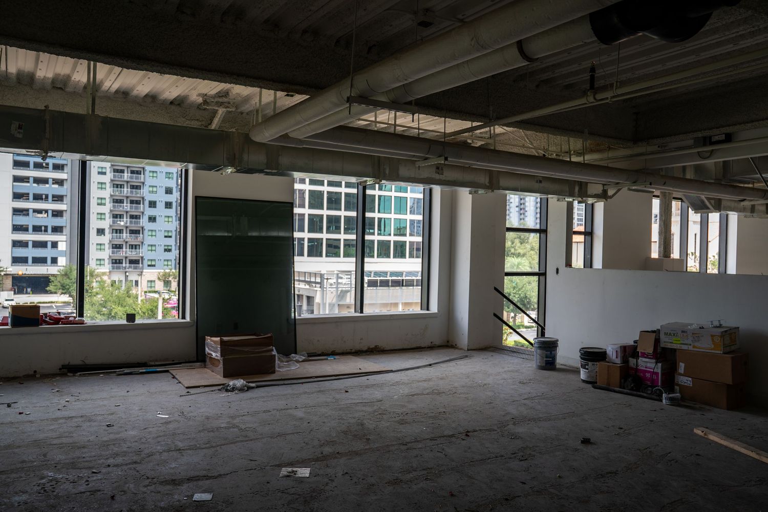 Panoramic view of an empty commercial space with large windows and exposed ceiling infrastructure.