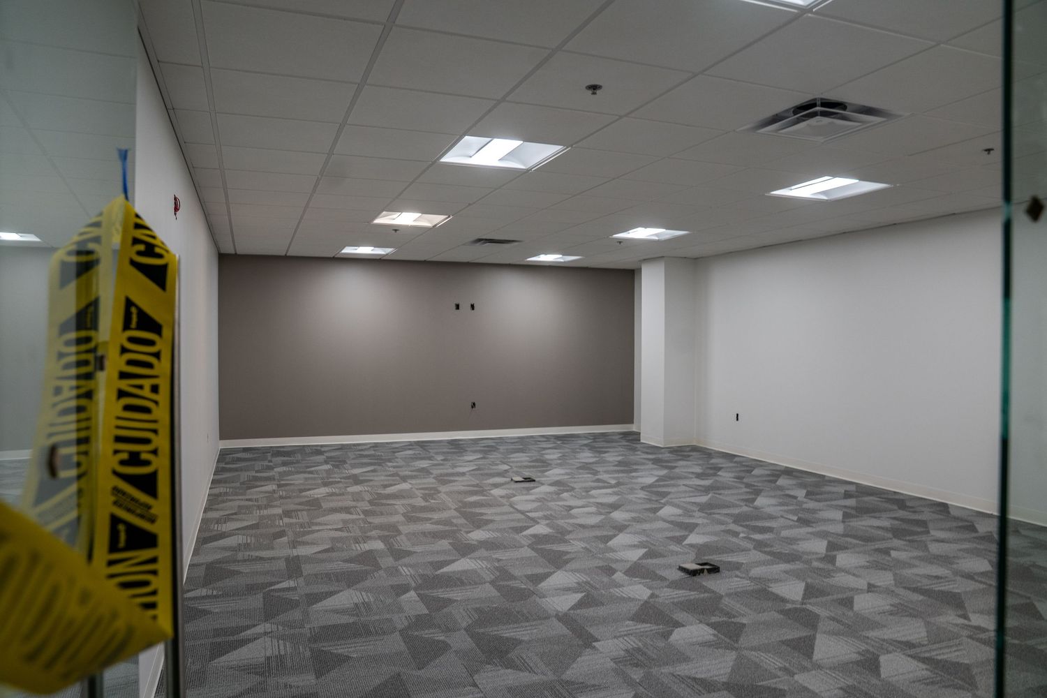 Commercial office space with new carpeting and caution tape during construction phase.