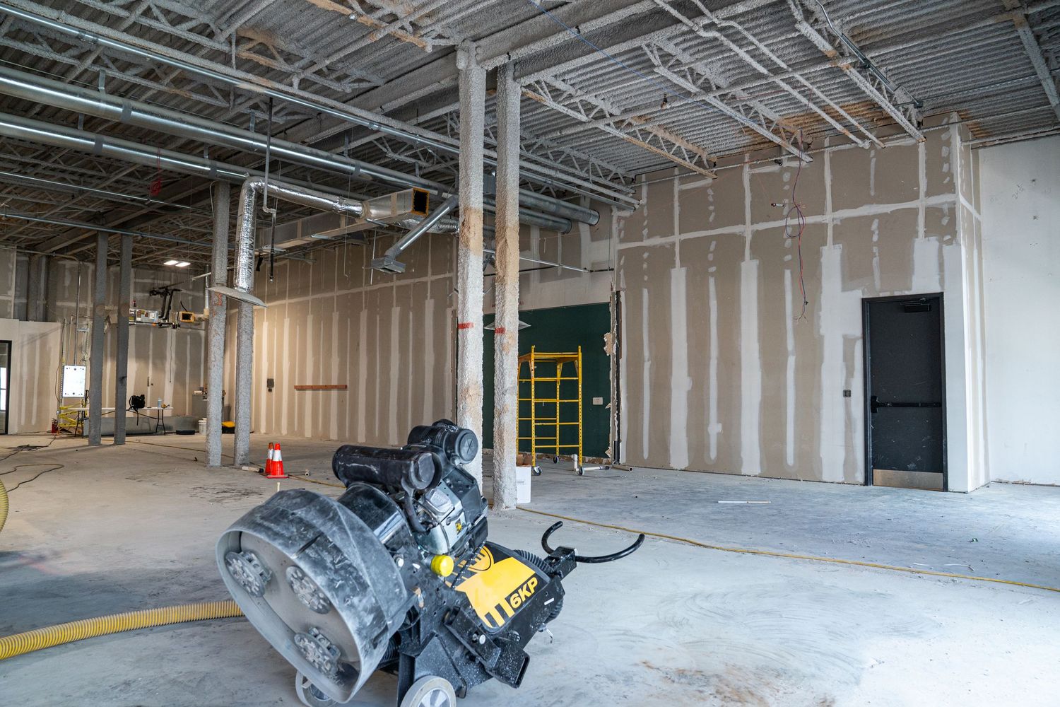Industrial space renovation showing exposed ductwork, ladders, and construction equipment.