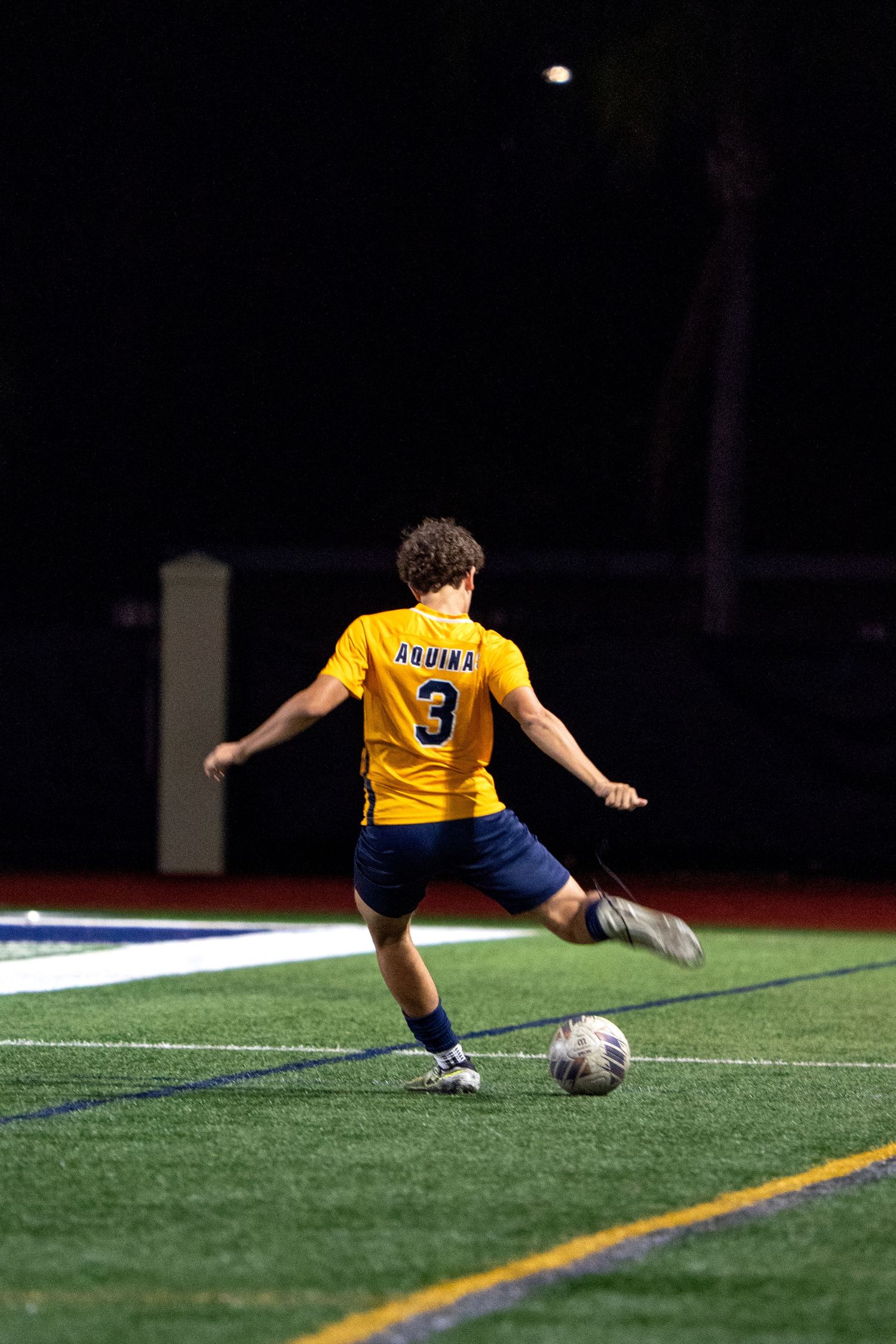 Soccer player in yellow jersey diving to make a save on artificial turf field.