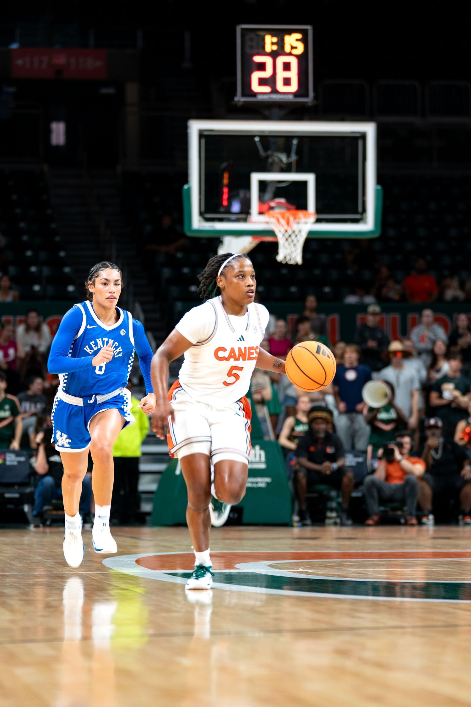 Basketball players in white and blue uniforms competing during fast break play.