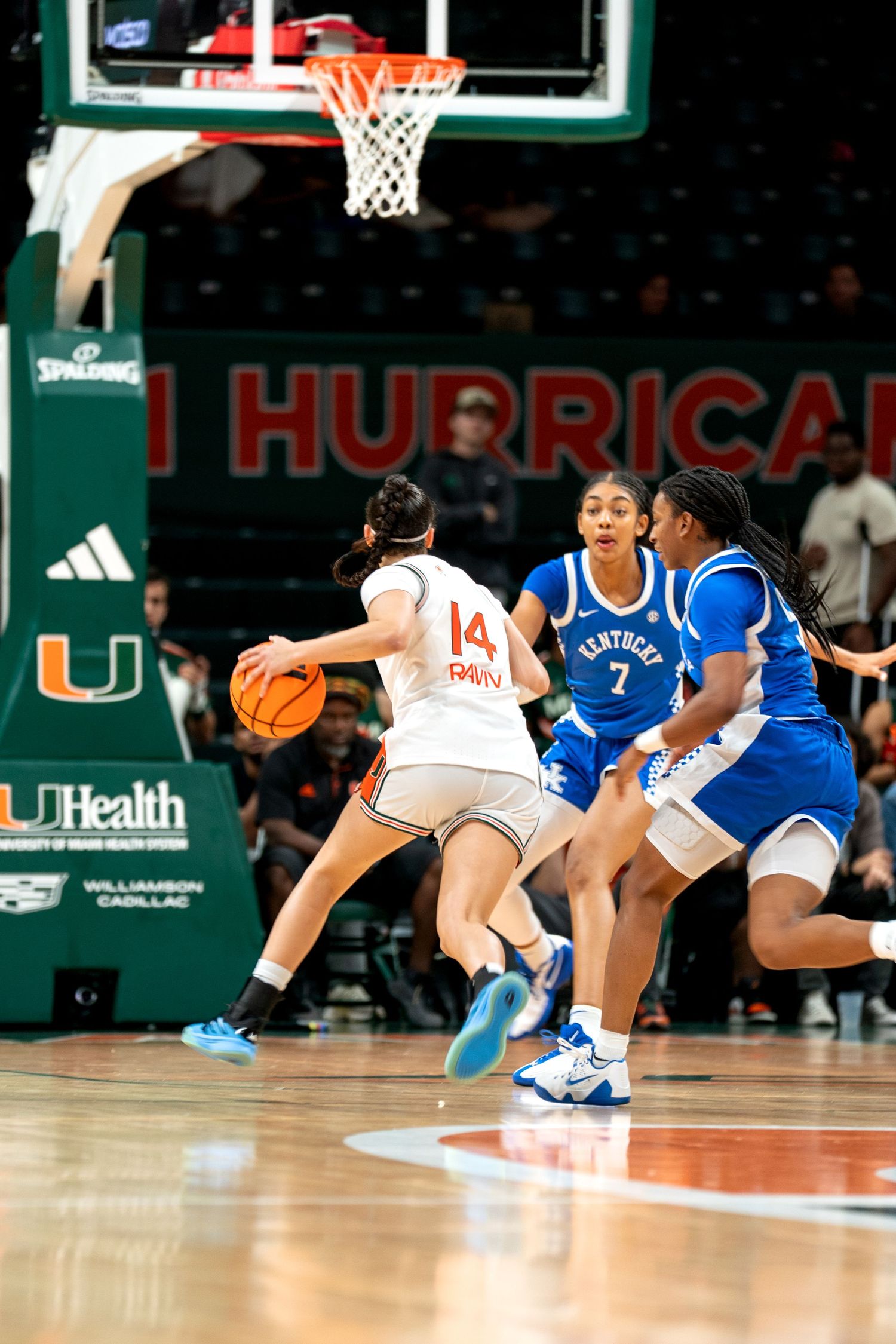 Basketball players compete on the court during a game between Miami and their opponents in white and blue uniforms.