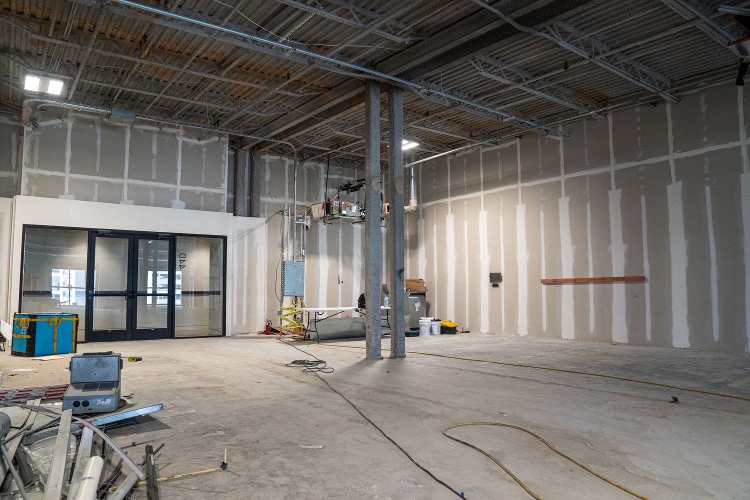 Large empty industrial space under renovation with exposed ductwork and white walls.
