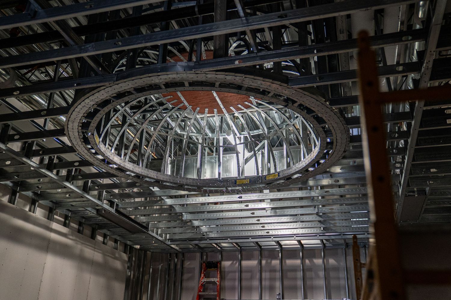 Large circular architectural detail in ceiling shows metal framework and construction progress.