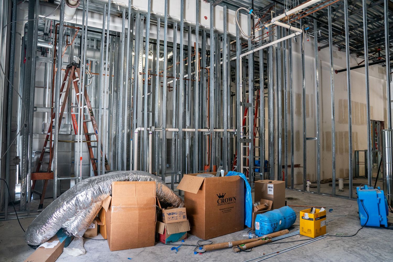 Wide angle view of commercial renovation showing metal framing and stored construction supplies.