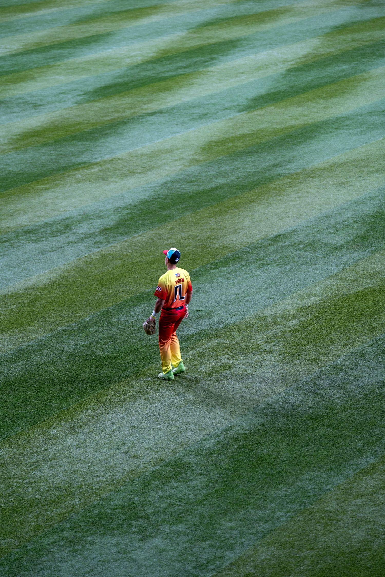 Soccer players in red and yellow uniforms run across a striped grass field during a match.